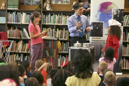 Angelica Gonzalez (left) and Kyara Pierce (right) help Jeff Evans (center) with a magic trick at the Renton Public Library. Librarians planned several events