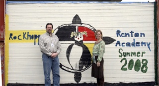 Michael Oliver is program facilitator and Lisa Hoyt is director of Renton Academy. They are pictured in front of a mural students painted of the school’s mascot