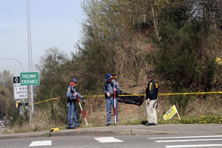 State troopers take measurements Monday where a stolen 2012 Chrysler sedan plowed up the side of an embankment just off Interstate 405 near Kennydale Elementary School. A piece of the car lies just beyond the investigators.