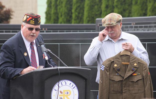 The son of a WWII vet holds his father's uniform and wipes away a tear as VFW Post leader Darrell Pilat reads an old poem during the 2015 Memorial Day event.