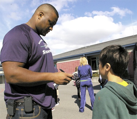 Seattle Seahawks offensive lineman Rob Sims signs an autograph for Talbot Hill Elementary School 4th-grader Steven Ho. Sims was at the school as part of the National Football Leagues PLAY 60 national youth health and fitness campaign which urges children to get at least 60 minutes of physical activity each day.