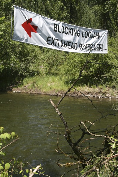 A sign over the Cedar River near Cedar Rapids upriver from Cavanaugh Pond warns recreationalists to get out of the river because of a large logjam ahead.