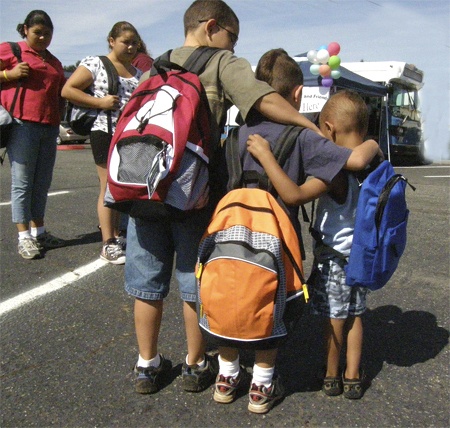 Renton School District students with new backpacks filled with supplies in the Cascade neighborhood. Buses filled with supplies served about 300 students Aug. 22 as a part of the Bridge the Gap program.