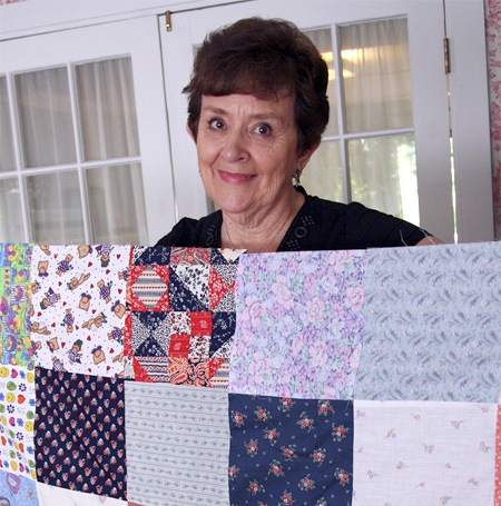 Renton's Lenore Lee holds up one of the about 500 quilt tops she's sewn for charity in the past 7 years.