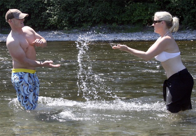 Jason and Kara Mirante of Maple Valley found some relief from the heat Thursday afternoon in the Cedar River near Carco Theater. Kara grew up in Renton and they wanted to introduce their son Hayden