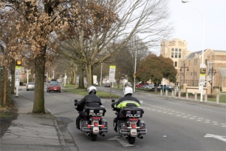Two Renton police officers  cruise down South Second Street in front of Renton High School. This four-lane stretch is one of the three Renton school zones monitored by cameras that are programmed to catch speeders.
