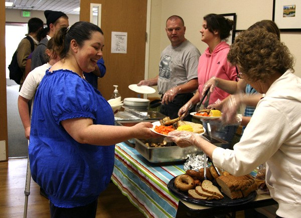 Kimm Baxter accepts a chicken dinner from volunteers at the Renton Community Supper. The supper opened Monday night at the Renton Salvation Army Church.