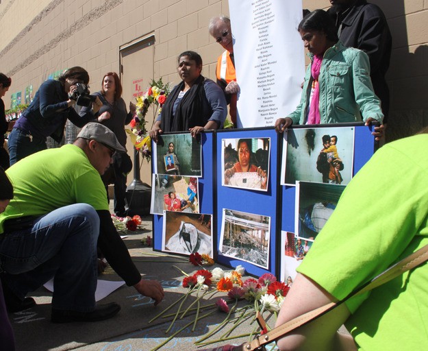 Protesters place flowers and write the names of fire victims during a protest Wednesday at the Renton Walmart.