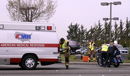 Renton Police officers push a touring motorcycle off southbound Rainier Avenue South that was involved in a collision with a car at about 12:15 p.m. Friday at Grady Way.  The motorcycle rider was walking after the collision. A private ambulance was called