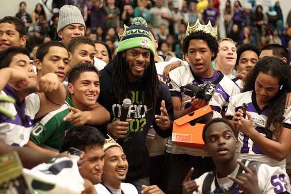 Richard Sherman surrounded by members of the Foster High School football team during an appearance at the school's homecoming pep rally. Sherman brought new cleats for each member of the team.