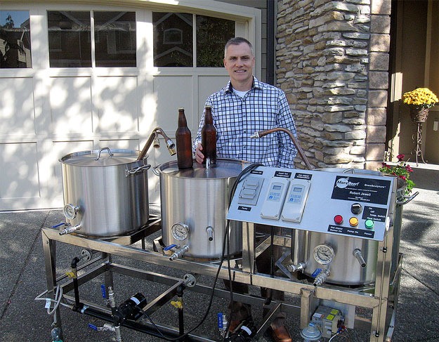 Robert Jewell of Renton uses his brewing system – his brewery – to brew beer outside on his driveway. Inside his garage is a cooler with beer kegs – and room to sip away.