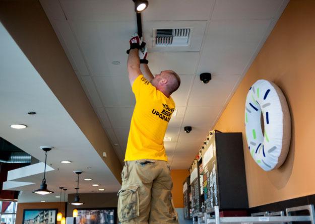 A worker for PSE installs energy efficient lights at Top Pot Doughnuts at The Landing.