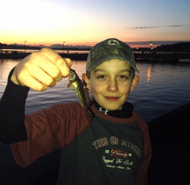 A beautiful sunset over Lake Washington provides the backdrop for this photo of Rutger Youch and his catch of a bullhead at Gene Coulon Park on March 12.