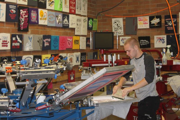 Lindbergh student Dirk Healy demonstrates how to use the school's manual screen printing machine.