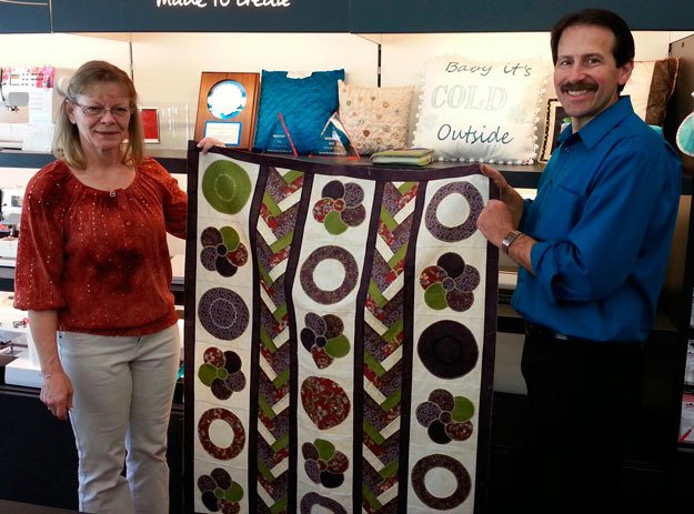 Cevin Waffle and Annette Goes display a quilt at their downtown store.