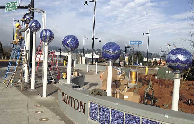 Artist Benson Shaw works to install the glass globes that make up part of 'Going Global' at the corner of Rainier Avenue South and Grady Way.