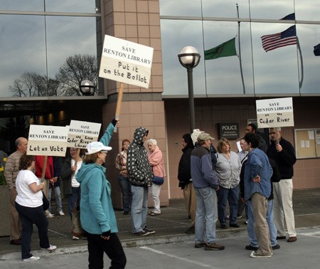 Karen Hensley of Renton paraded back and forth with her Save Renton Library Monday evening in front of City Hall before the City Council meeting. The council voted 4-3 to decline to place on the ballot an initiative to keep the library over the Cedar River. BELOW: Renton City Council member Ed Prince