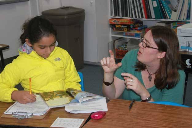A teacher at the Northwest School for Hearing-Impaired Children signs instructions on an assingnment.