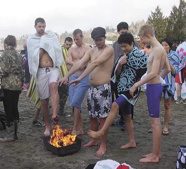 Residents warm themselves near a fire after plunging into Lake Washington Jan. 1.
