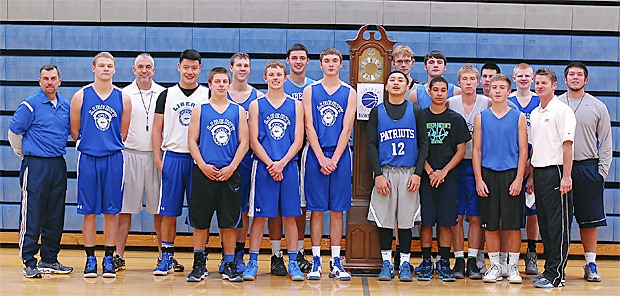 The Liberty High School boys basketball team stands near a grandfather clock to mark when their Midnight Madness practice started.