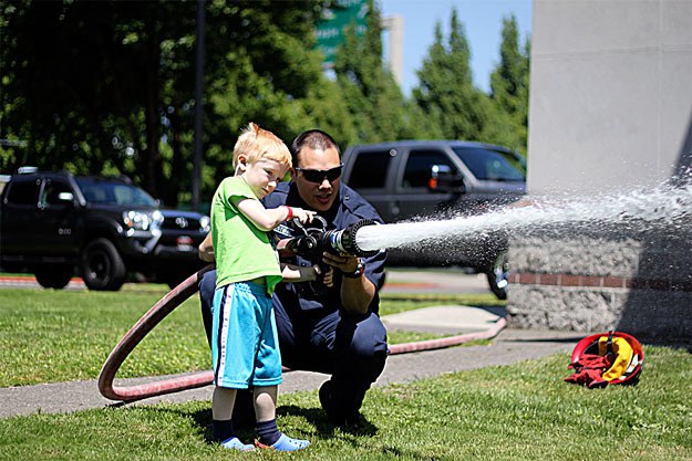 Firefighter helps a kid shoot the fire hose at Tuesday’s ‘BBQ with Badges’ event. The weather couldn’t be nicer to hang out with police officers and firefighters