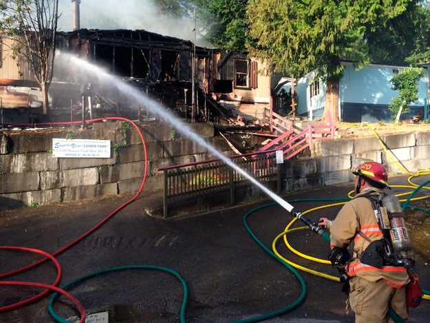 A firefighter battles a blaze at a mobile home park in Skyway.