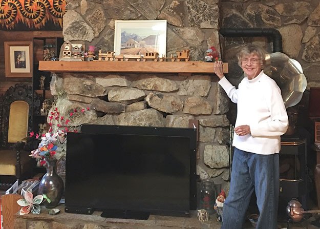 Barbara Nilson poses for a photo near the mantle of her Renton log cabin.