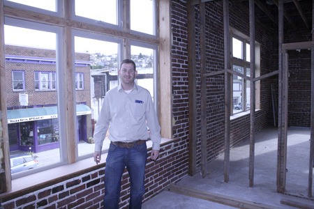 Owner Dave Smith stands next to the brick and original timbers that make up the interior of the Louisa building on Wells Avenue South downtown. Smith is turning the building’s second floor into office space.