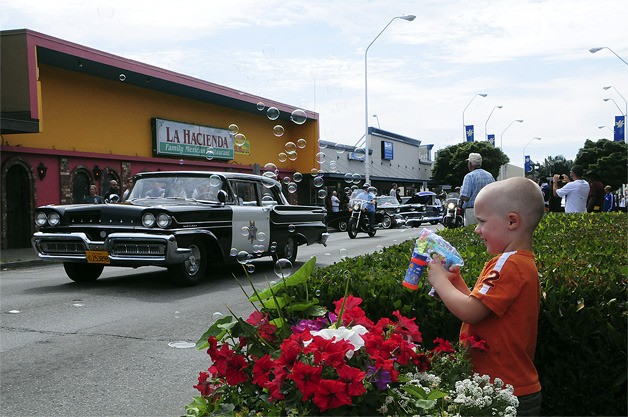 ABOVE: Mason Reznik gives a bubbly send off to a restored Mercury CHP squad car attending the Return to Renton car show.