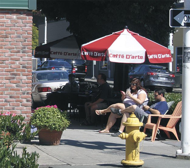 Residents soak in the sunshine while enjoying a beverage downtown during a sunny and warm Monday afternoon in Renton.