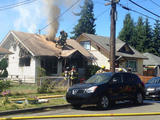 Firefighters cut a hole in the roof of a home in North Renton on July 24 to vent smoke and heat.