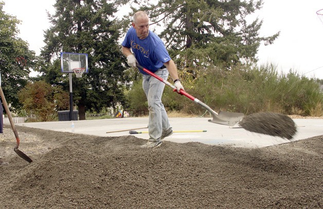 Microsoft employee Dave LeFevre shovels gravel around the edge of a basketball court near Vision House.