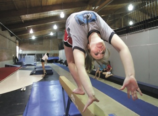 Standout Lindbergh gymnast Louise Baker performs a back walk-over on beam in practice at Lindbergh.