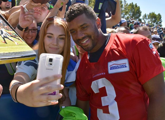 Seahawks quarterback Russell Wilson poses for a selfie with a fan at Seahawks Training Camp