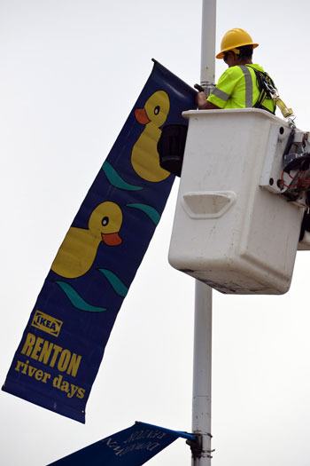 City workers hang the Renton River Days banners on street lights downtown.
