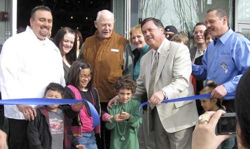 Benicio Bryant cuts the ribbon at Rain City Catering grand opening and ribbon-cutting Thursday at the Renton Pavilion Event Center at the Piazza in downtown Renton. Looking on are co-owner and father Jeremy Bryant