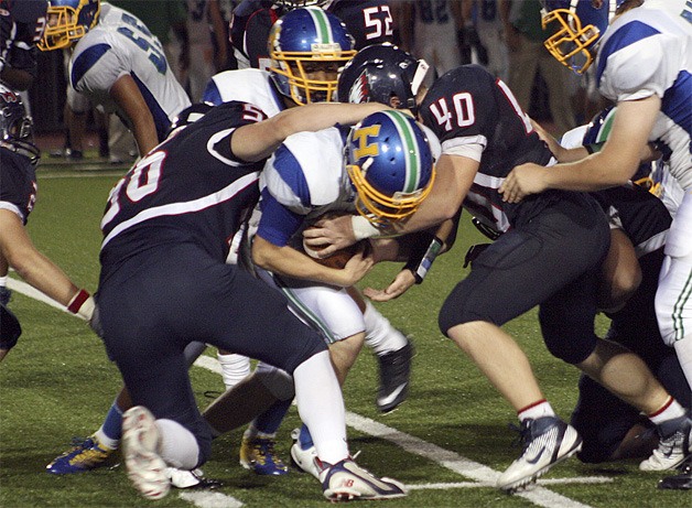 Lindbergh's Connor Forbes (56) and Daniel Wiitanen (40) bring down Hazen's Kyle Nelson for a loss.