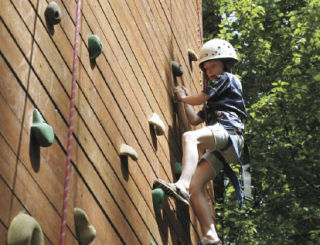 Ashley Pritchard climbs up the rock wall at the summer camp recently at the Camp Cedar River at the Renton Lions Youth Camp.