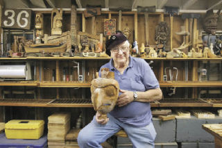 Master woodcarver Jim Ploegman poses in his shop and classroom with a hawk mask he made in the Northwest coast style. It and other masks will be on display at IKEA Renton River Days.