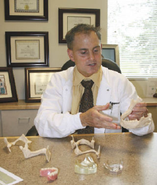 Dr. Robert Odegard displays some of the models he uses to explain how mini-dental implants are used.