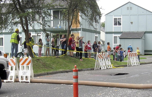 Kids line up on a berm just feet from a 16-foot sinkhole at Royal Hills Apartments.