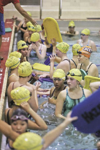 The Hazen girls swim team gathers against the pool wall to start a set in practice Tuesday.