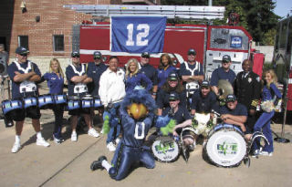 A large crowd attended the dedication Saturday of the “12th Man Engine” at Fire Station 12 in Renton. The Seahawks theme is in recognition of the fact that Fire Station 12 provides fire coverage to the team’s new headquarters on Lake Washington. Mayor Denis Law (in white) is surrounded by the Seattle Seahawks’ Blue Thunder drum line