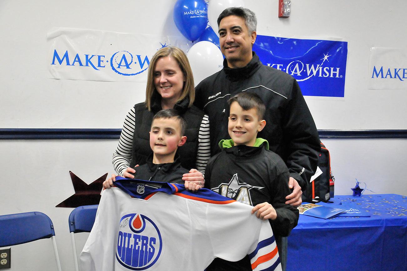 Zach Cezar (front left) was surprised Monday at Sno-King Ice Arena in Renton with a trip to his NHL All-Star game Saturday in Los Angeles. Cezar and his parents and brother pose with a Edmonton Oilers jersey he received as part of his wish. (Leah Abraham | Renton Reporter)