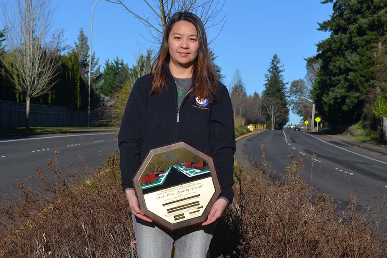 Flora Lee, a civil engineer with the city of Renton, poses on Duvall Avenue with her American Public Works Association award. She was the manager for the Duvall Avenue pavement restoration project, which added an estimated 12-15 years to the life of the roadway. (Courtesy photo)