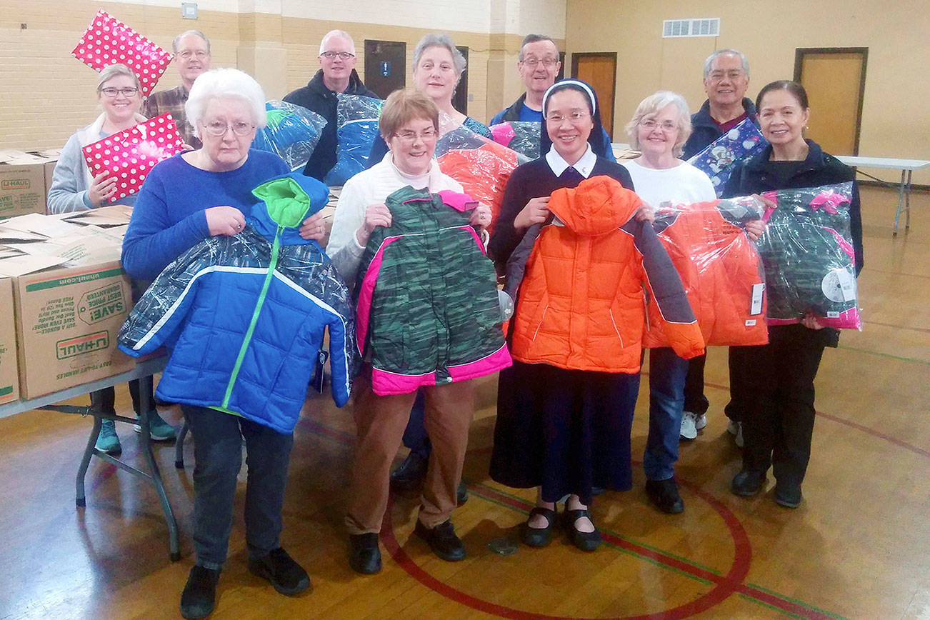 St. Anthony parishioners hold up coats they are donating to the “Coats for Kids” effort. (Courtesy photo)