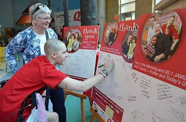Maddy Betlach, right, signs a poster at a Radiothon event. Courtesy photo