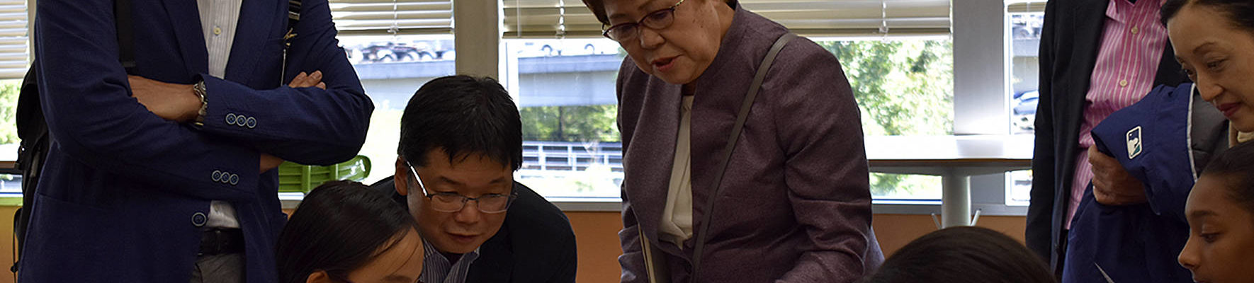 Photo by Haley Ausbun. Japan congress members observe a sixth grader at Renton Prep as she works on her Minecraft museum project.