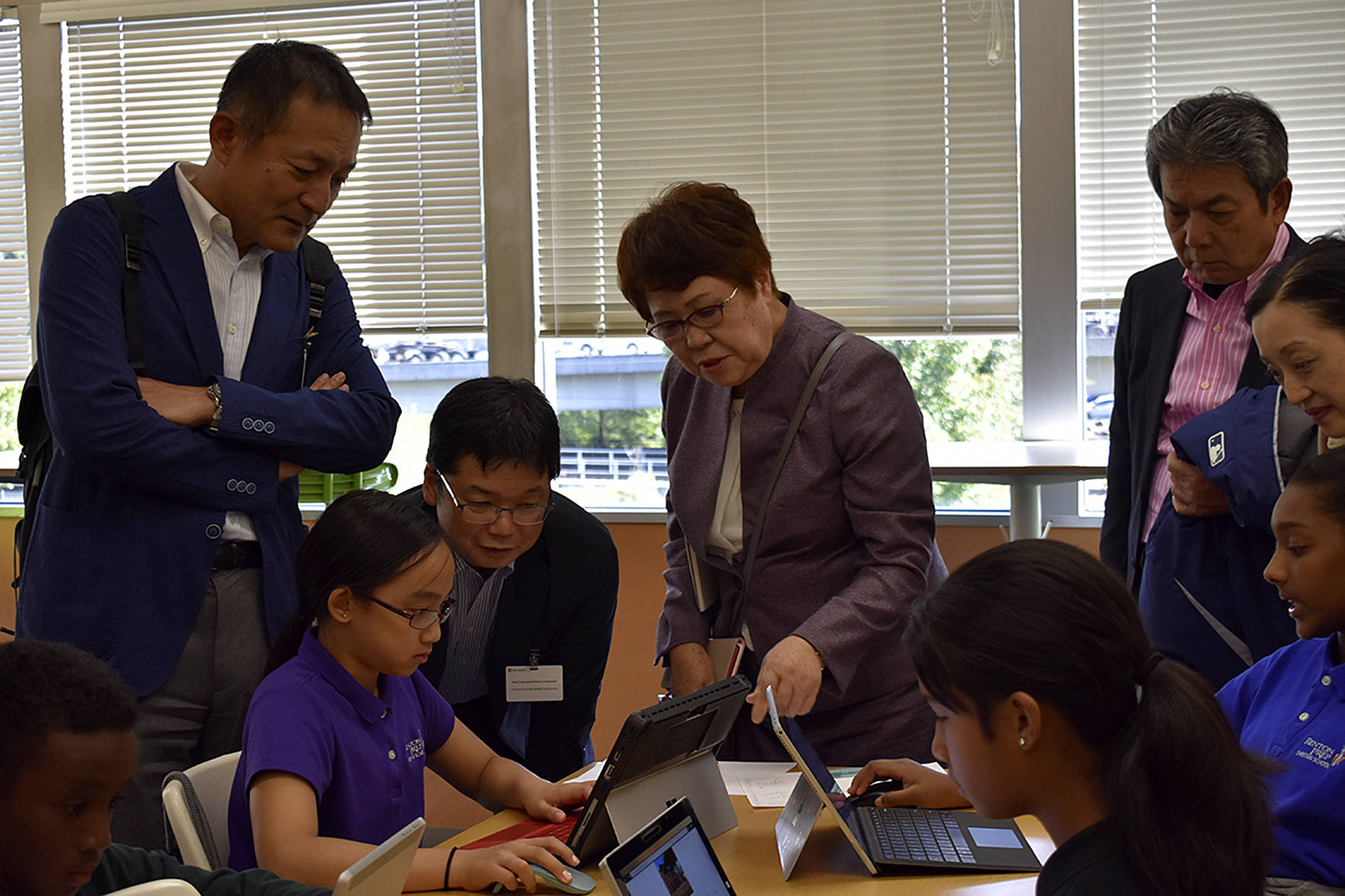 Photo by Haley Ausbun. Japan congress members observe a sixth grader at Renton Prep as she works on her Minecraft museum project.