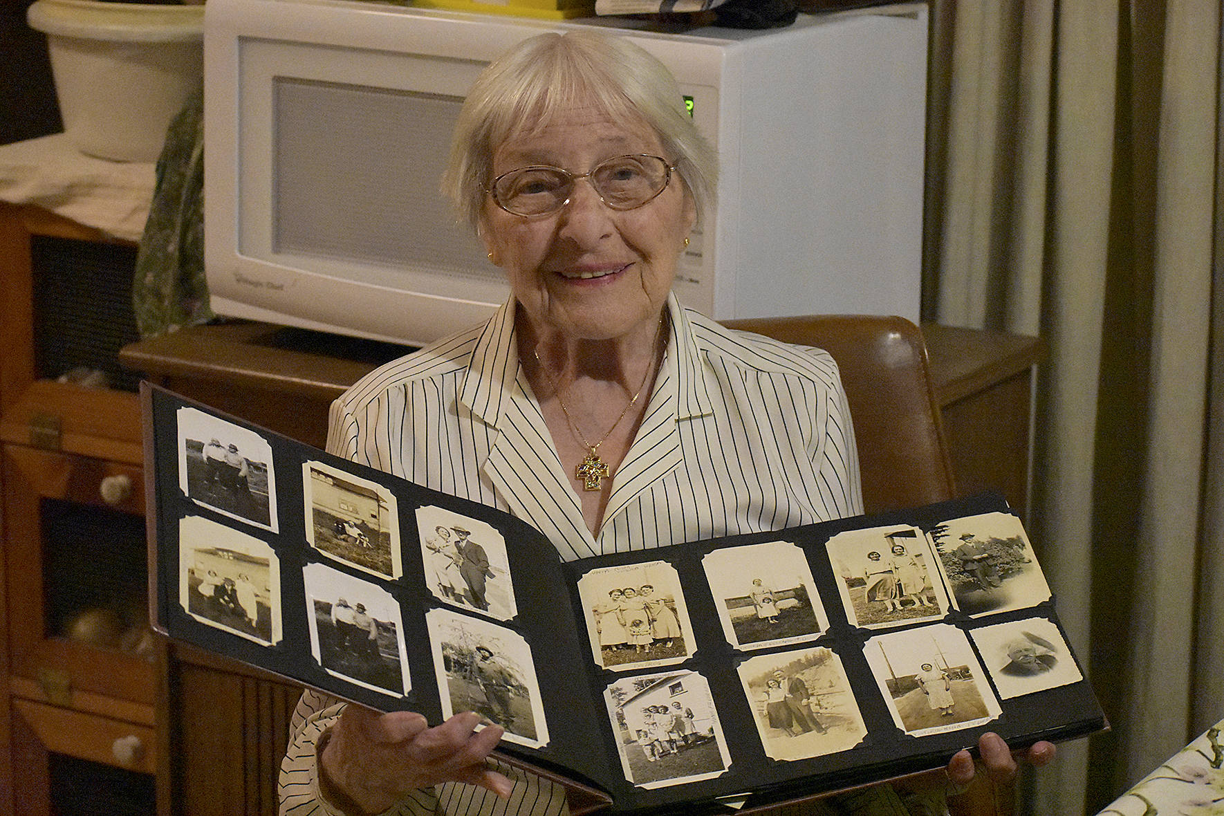 Photo by Haley Ausbun.                                Wanda “Noni” Capellaro reflects on 100 years in Renton, looking at photos of friends and family past.
